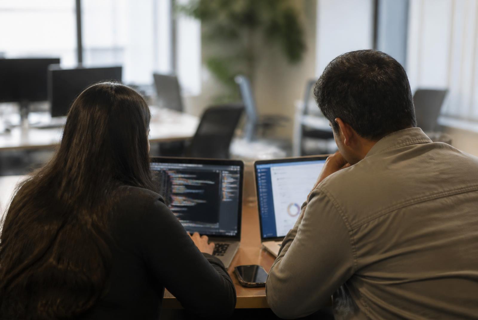 Two Avensus specialists working together at a laptop in the office
